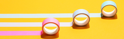 Three rolls of colored tape on a yellow background